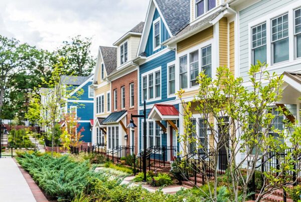 Homeowners Association Insurance - Row of Colorful, Red, Yellow, Blue, White, and Green Painted Residential Townhouses With Brick Patio in the Summer